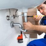 Plumber fixing sink pipes in a bathroom